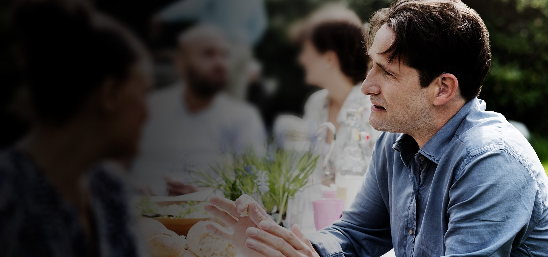 Man at table wearing Oticon Dynamo super power hearing aids-1920x900